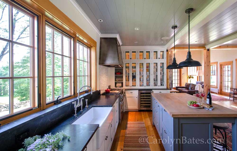 Example of a classic light wood floor kitchen design in Burlington with a farmhouse sink, shaker cabinets, stainless steel appliances and an island