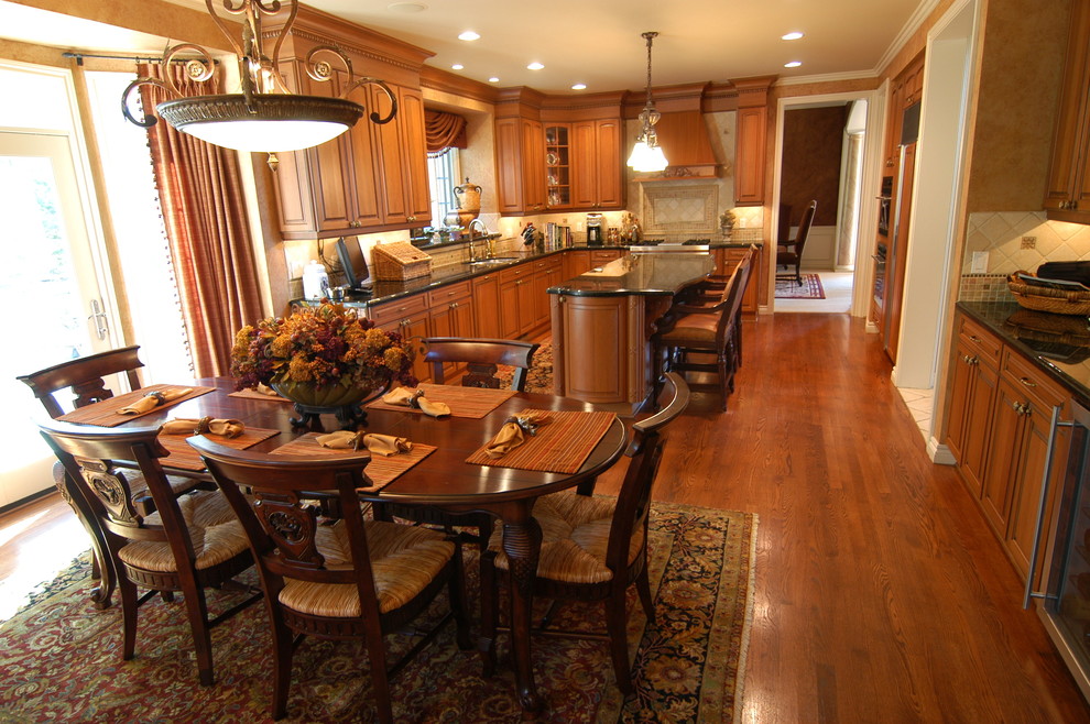 Exempel på ett stort klassiskt kök, med en dubbel diskho, luckor med upphöjd panel, skåp i mellenmörkt trä, granitbänkskiva, beige stänkskydd, integrerade vitvaror, mörkt trägolv, en köksö, stänkskydd i stenkakel och brunt golv