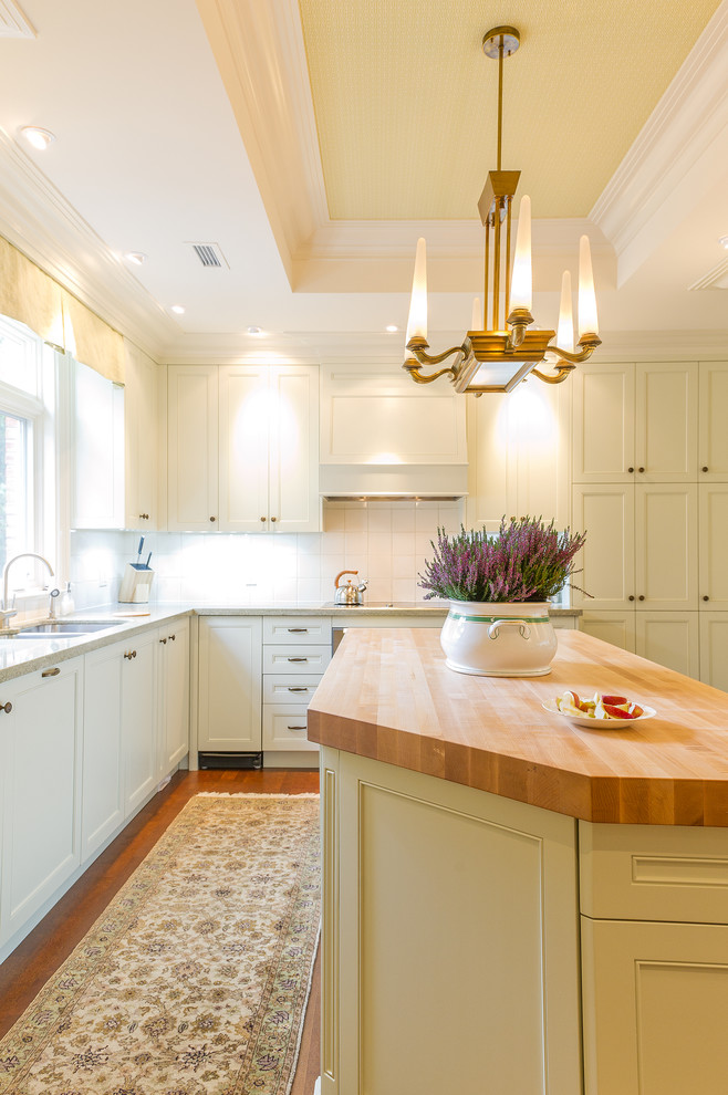 Large classic kitchen in Toronto with a double-bowl sink, recessed-panel cabinets, white cabinets, white splashback, medium hardwood flooring and an island.