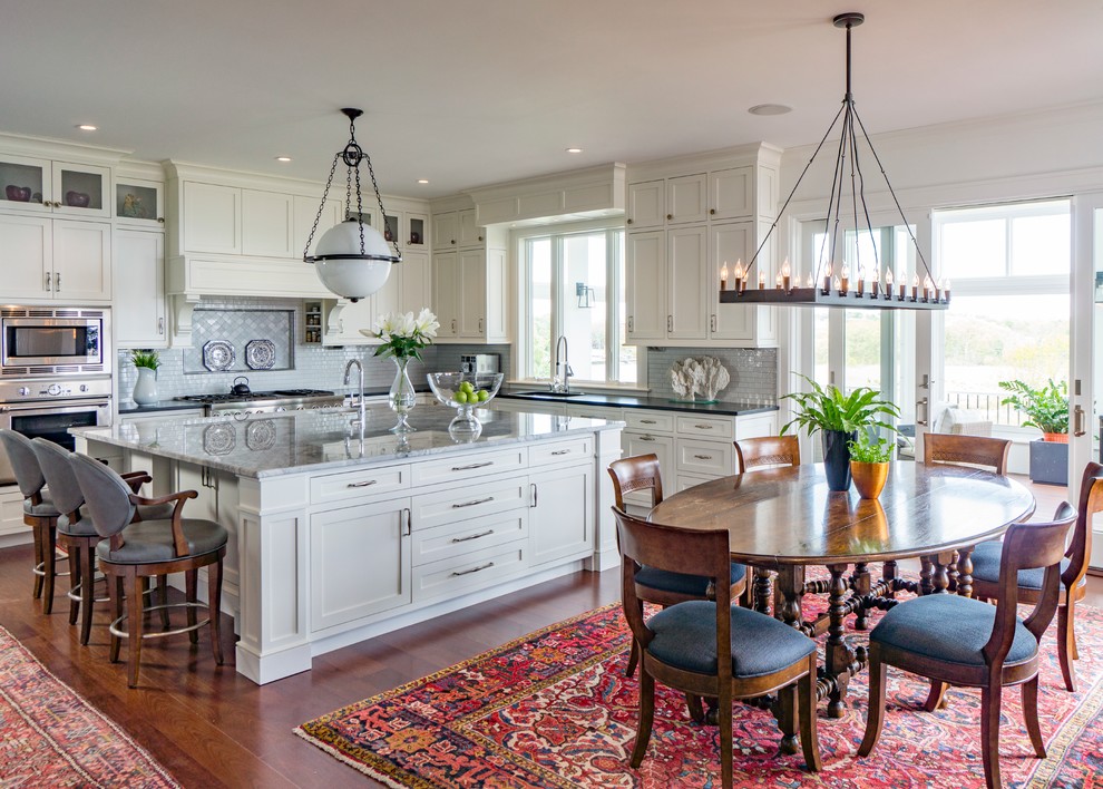 Klassische Wohnküche in L-Form mit Schrankfronten im Shaker-Stil, weißen Schränken, Küchengeräten aus Edelstahl, braunem Holzboden, Kücheninsel, Marmor-Arbeitsplatte und Küchenrückwand in Grau in Boston