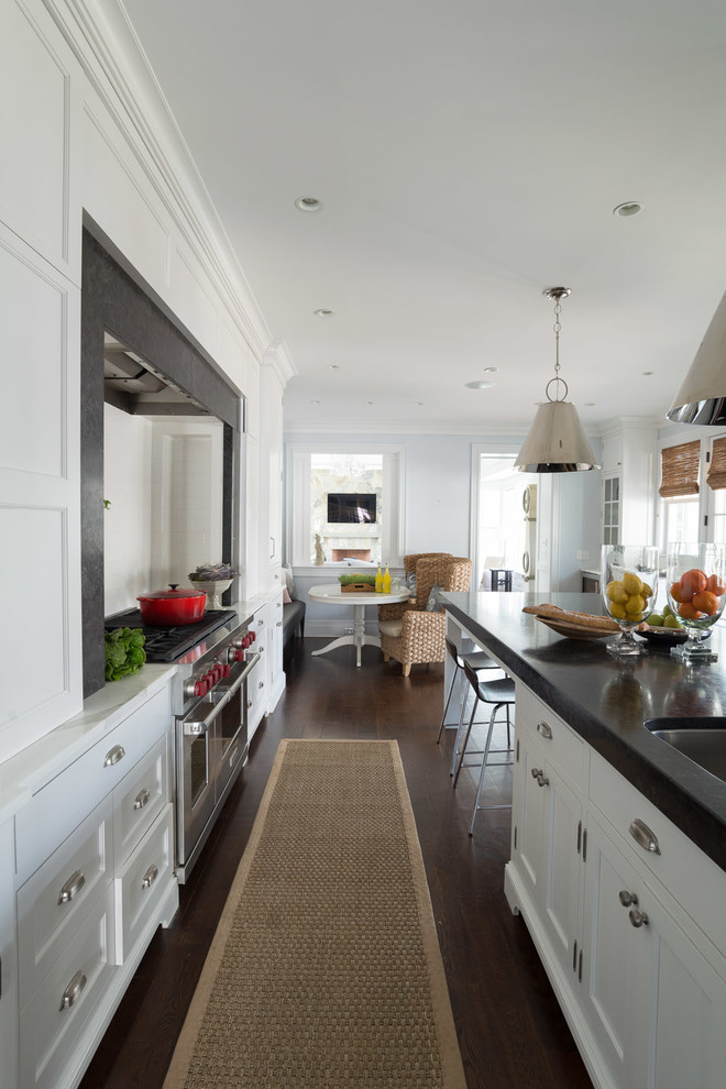 Design ideas for a traditional kitchen/diner in New York with white cabinets, white splashback, metro tiled splashback, dark hardwood flooring, an island, a submerged sink, recessed-panel cabinets and stainless steel appliances.