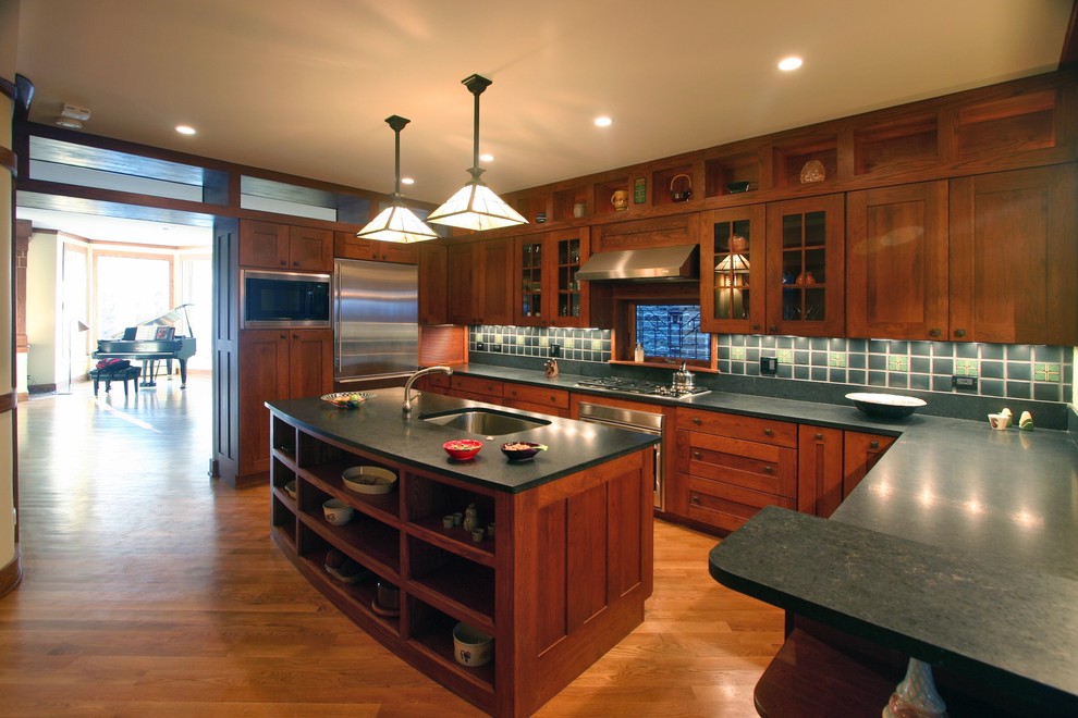 Modelo de cocina clásica con armarios estilo shaker, electrodomésticos de acero inoxidable, fregadero bajoencimera, puertas de armario de madera en tonos medios y salpicadero gris