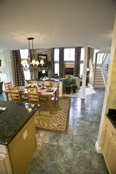 Стильный дизайн: большая угловая кухня-гостиная в классическом стиле с фасадами с выступающей филенкой, черной техникой, полом из керамической плитки и островом - последний тренд