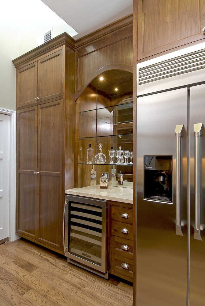 На фото: кухня в классическом стиле с техникой из нержавеющей стали и фасадами цвета дерева среднего тона