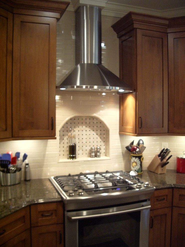 Example of a large classic single-wall open concept kitchen design in Cleveland with shaker cabinets, medium tone wood cabinets, granite countertops, white backsplash, ceramic backsplash, stainless steel appliances and an undermount sink