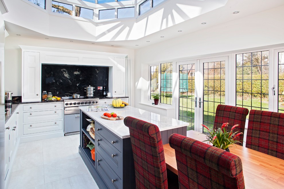 This is an example of a traditional l-shaped kitchen/diner in West Midlands with recessed-panel cabinets, white cabinets, stainless steel appliances and an island.