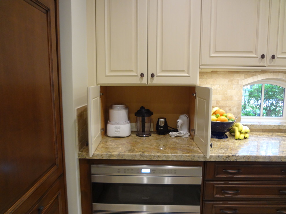 Elegant kitchen photo in Houston with white cabinets and beige backsplash