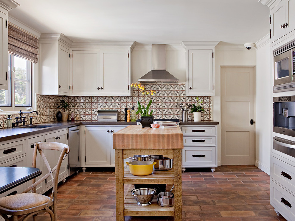 Traditional l-shaped kitchen in Los Angeles with engineered stone countertops, an island, a submerged sink, shaker cabinets, beige cabinets, multi-coloured splashback, stainless steel appliances and terracotta flooring.