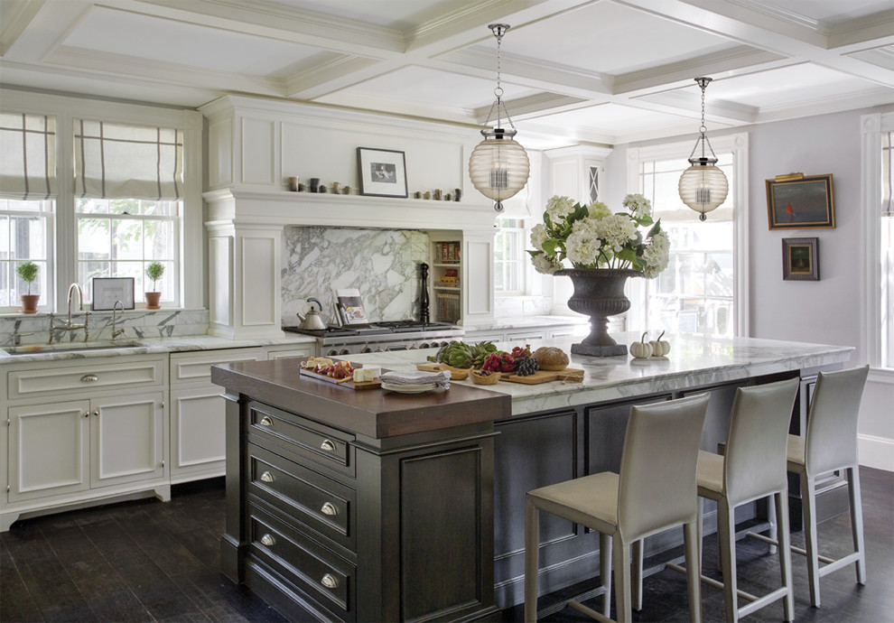 Photo of a large traditional l-shaped kitchen/diner in Other with a submerged sink, recessed-panel cabinets, white cabinets, marble worktops, white splashback, marble splashback, white appliances, dark hardwood flooring, an island, brown floors and white worktops.