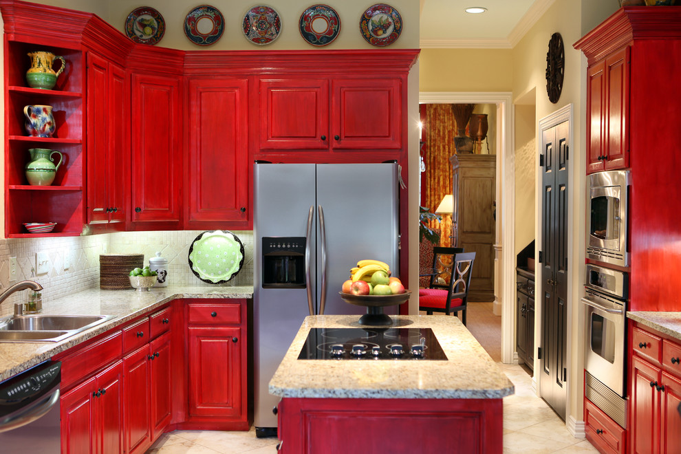Klassisk inredning av ett kök, med granitbänkskiva, rostfria vitvaror, röda skåp, en nedsänkt diskho, luckor med upphöjd panel, beige stänkskydd, stänkskydd i mosaik, travertin golv och en köksö