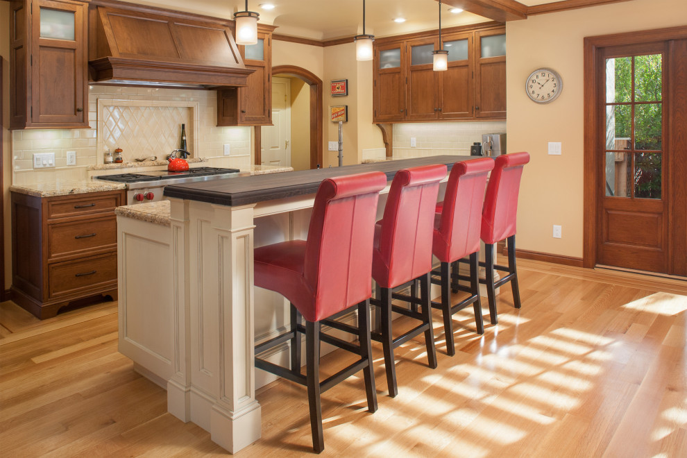 Exempel på ett klassiskt flerfärgad flerfärgat kök och matrum, med en undermonterad diskho, luckor med profilerade fronter, skåp i ljust trä, granitbänkskiva, beige stänkskydd, stänkskydd i keramik, rostfria vitvaror, ljust trägolv, en köksö och brunt golv