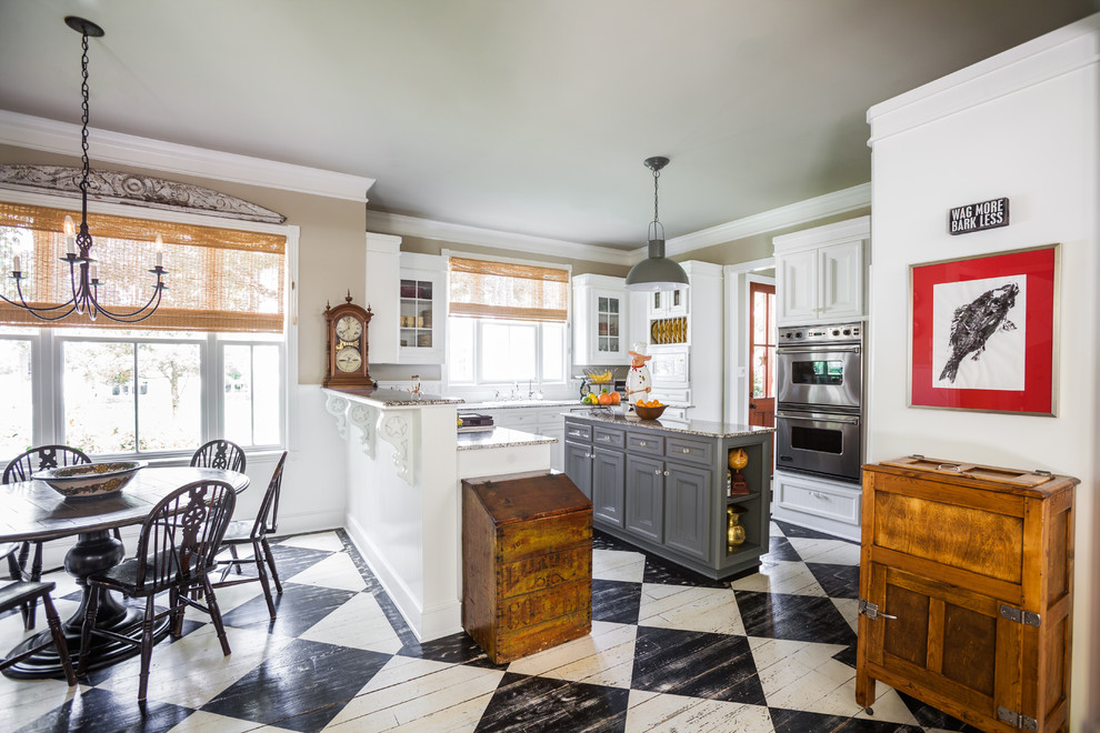 Modelo de cocina clásica con armarios con paneles empotrados, puertas de armario blancas, electrodomésticos de acero inoxidable, suelo de madera pintada y una isla