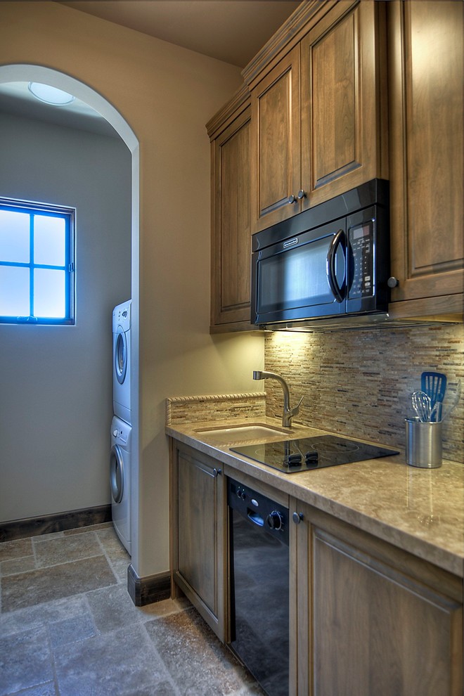 Cette photo montre une petite cuisine ouverte parallèle chic en bois brun avec un évier encastré, une crédence beige, un électroménager noir et machine à laver.