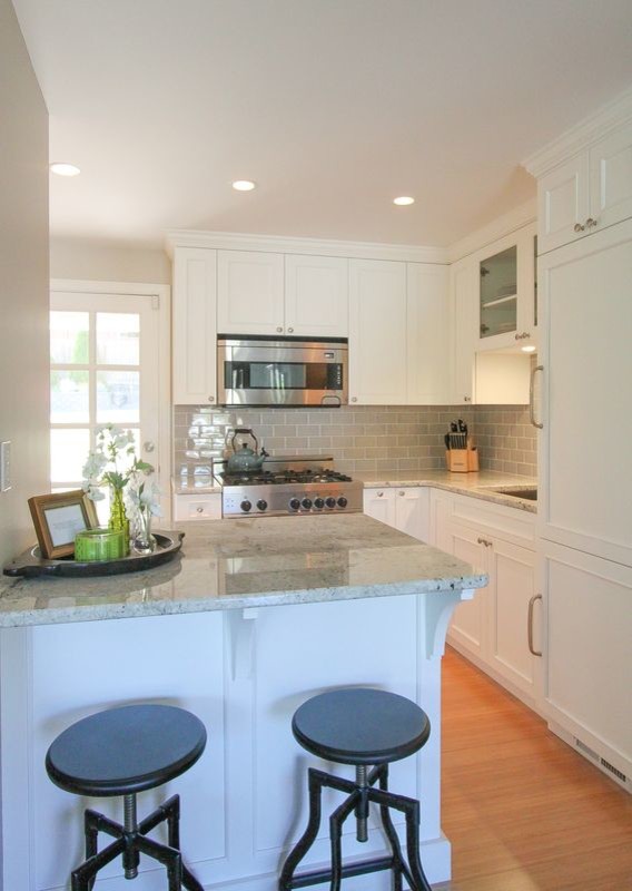Small elegant l-shaped bamboo floor eat-in kitchen photo in Seattle with an undermount sink, recessed-panel cabinets, white cabinets, granite countertops, gray backsplash, ceramic backsplash, stainless steel appliances and an island