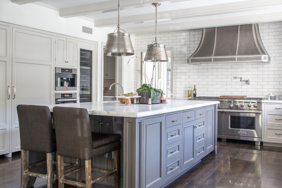 Design ideas for a classic grey and white kitchen in Los Angeles with recessed-panel cabinets, white cabinets, white splashback, metro tiled splashback, stainless steel appliances, dark hardwood flooring and an island.