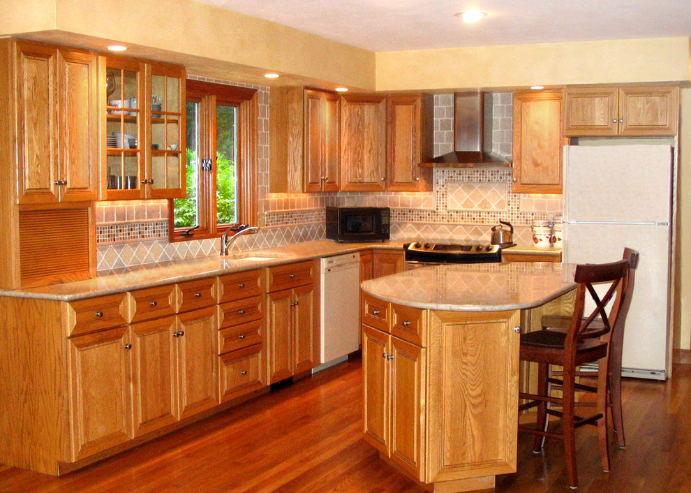 Mid-sized elegant l-shaped medium tone wood floor eat-in kitchen photo in Boston with an undermount sink, raised-panel cabinets, light wood cabinets, granite countertops, multicolored backsplash, stone tile backsplash, stainless steel appliances and an island
