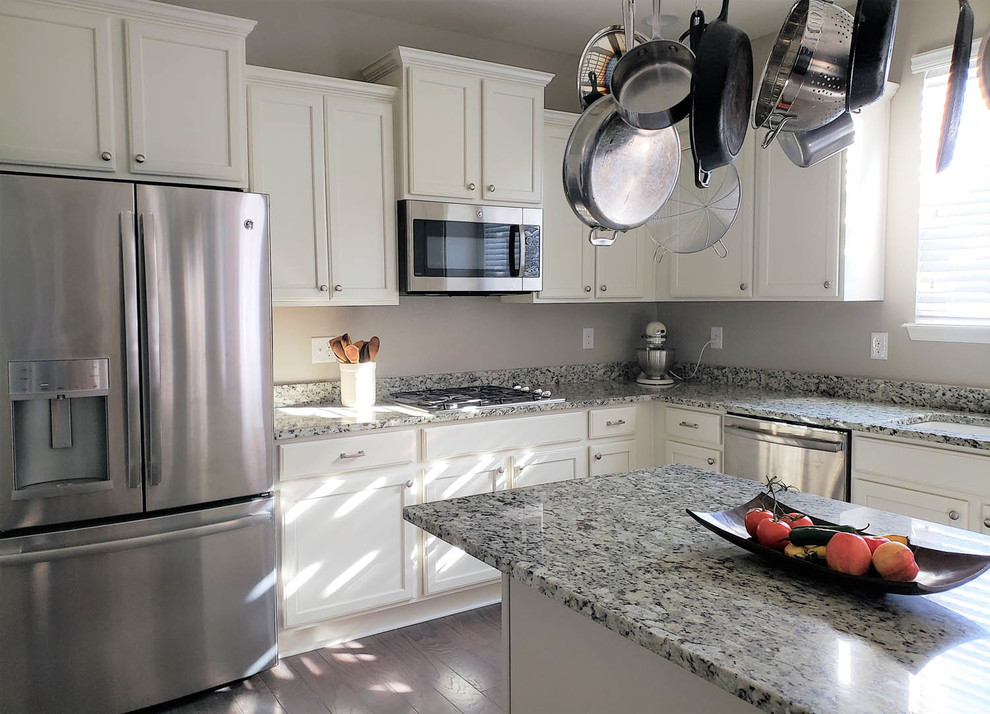 Foto på ett stort vintage flerfärgad u-kök, med en undermonterad diskho, luckor med infälld panel, vita skåp, granitbänkskiva, rostfria vitvaror, mörkt trägolv, en köksö och blått golv