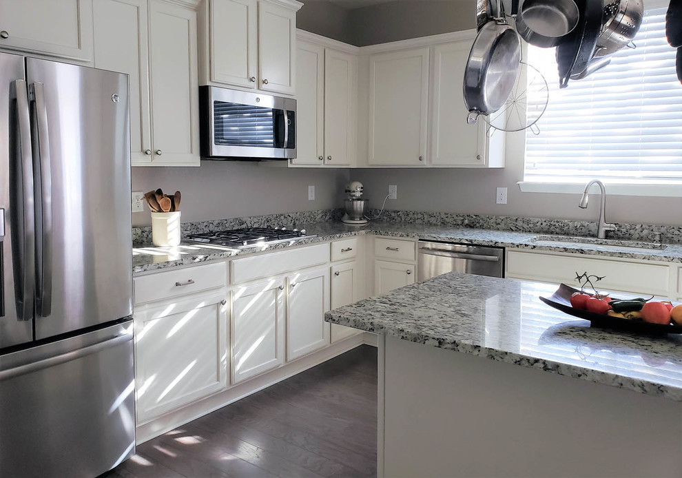 This is an example of a large traditional u-shaped kitchen in Denver with a submerged sink, recessed-panel cabinets, white cabinets, granite worktops, stainless steel appliances, dark hardwood flooring, an island, blue floors and multicoloured worktops.