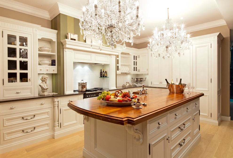 Foto di una cucina chic di medie dimensioni con ante a filo, ante bianche, top in legno, paraspruzzi bianco, parquet chiaro e lavello stile country