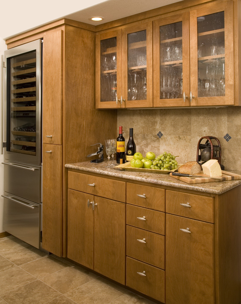 Elegant kitchen photo in Denver with flat-panel cabinets, stainless steel appliances, granite countertops, medium tone wood cabinets, brown backsplash and travertine backsplash