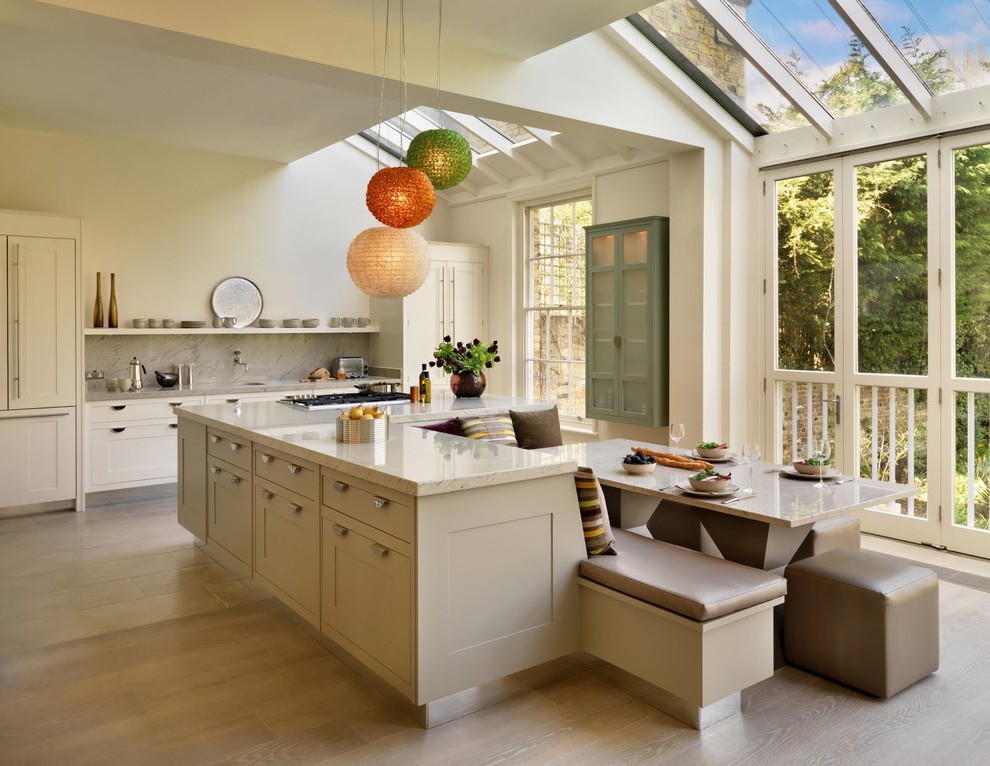 Cette image montre une cuisine américaine traditionnelle avec un placard à porte shaker, des portes de placard beiges, parquet clair et îlot.