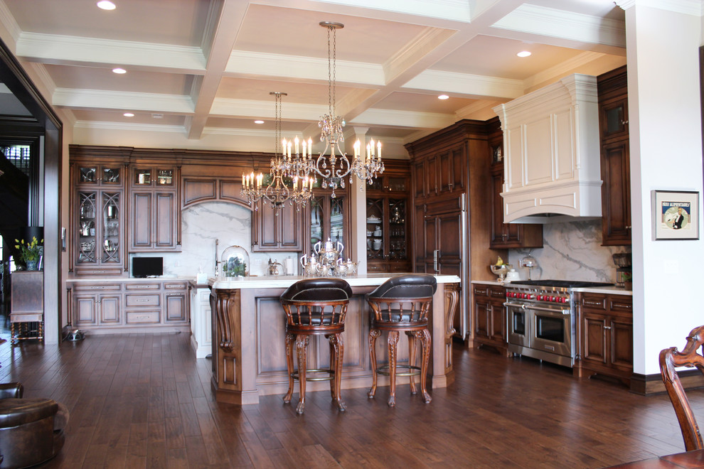 Example of a huge classic l-shaped dark wood floor and brown floor kitchen design in Other with recessed-panel cabinets, medium tone wood cabinets, white backsplash, stainless steel appliances, two islands and white countertops