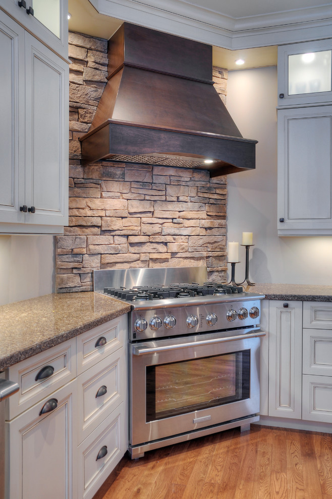 Ejemplo de cocina clásica con salpicadero beige, salpicadero de azulejos de piedra, electrodomésticos de acero inoxidable y suelo de madera en tonos medios