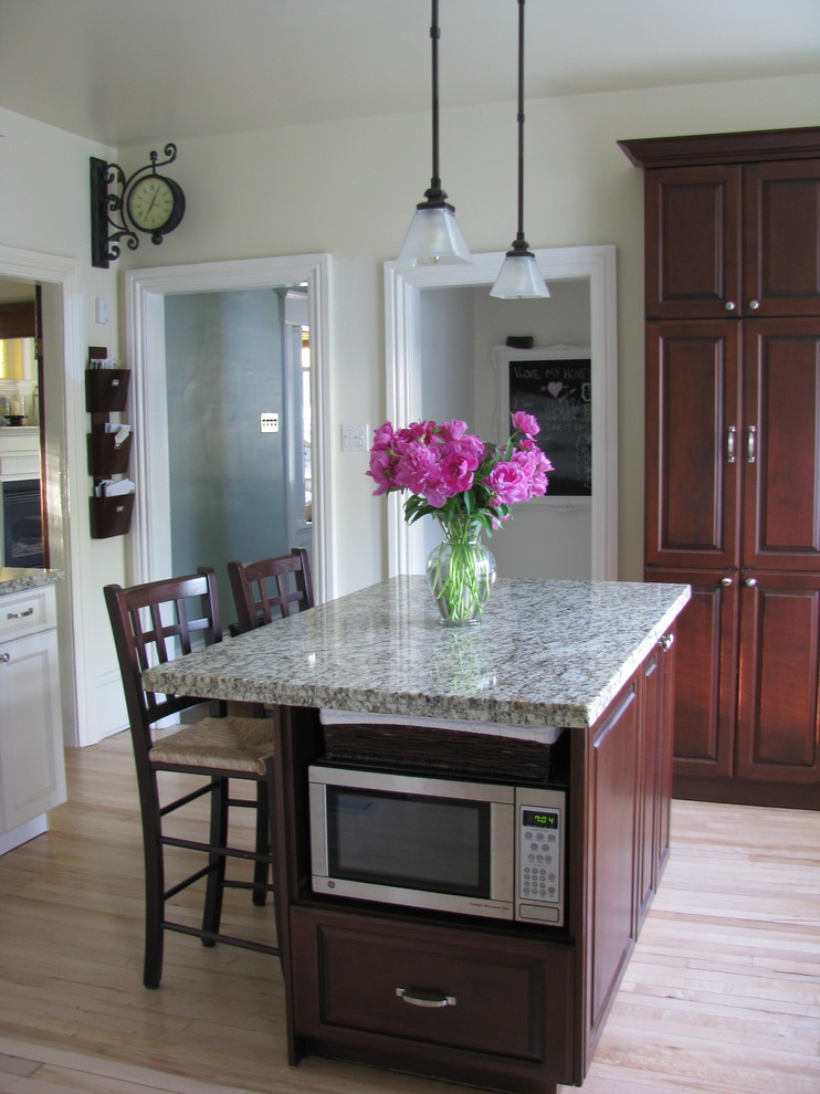 This is an example of a traditional kitchen in Toronto with raised-panel cabinets and dark wood cabinets.