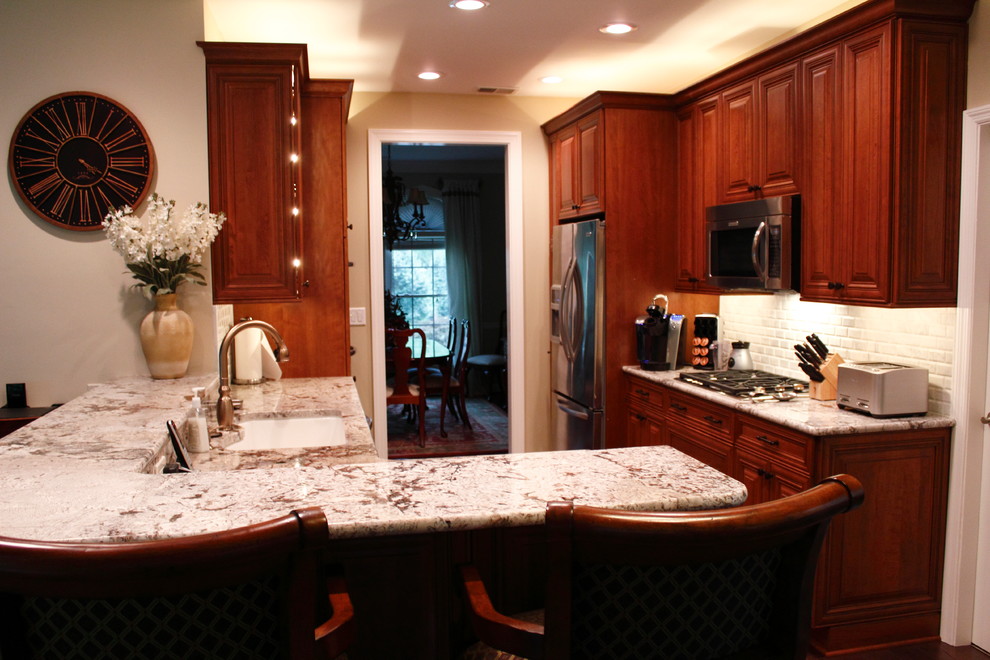 Example of a mid-sized classic galley medium tone wood floor eat-in kitchen design in Atlanta with an undermount sink, raised-panel cabinets, medium tone wood cabinets, soapstone countertops, multicolored backsplash, stone tile backsplash, colored appliances and a peninsula