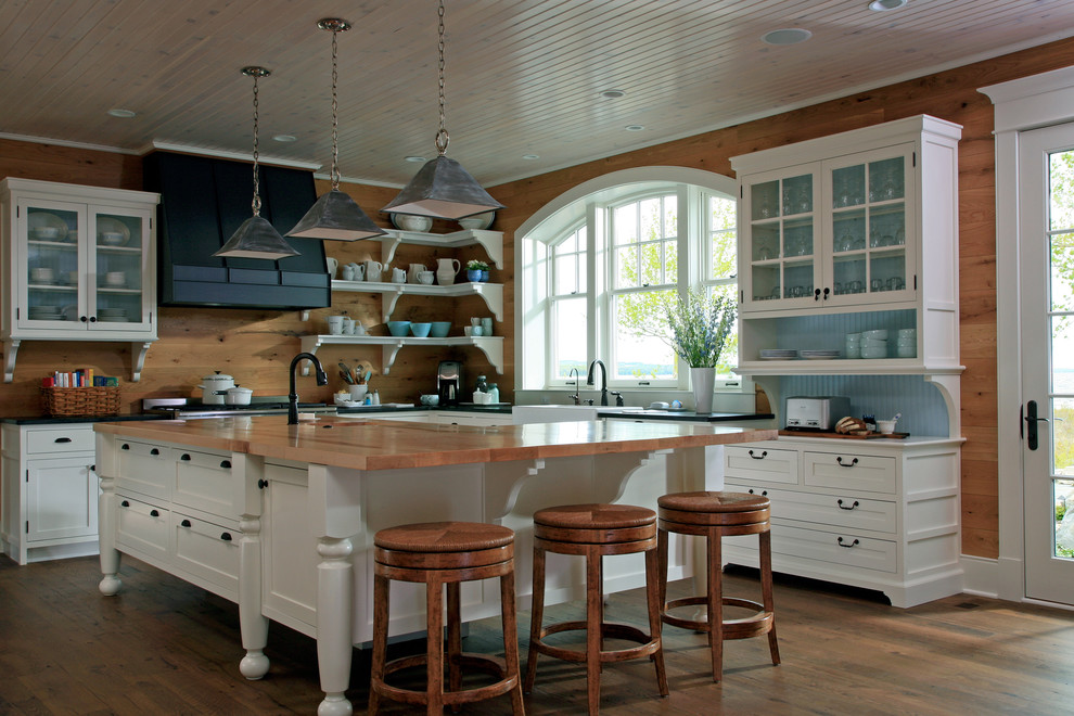 Foto de cocina clásica con armarios tipo vitrina, electrodomésticos de acero inoxidable y encimera de madera