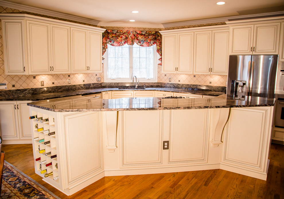 Example of a mid-sized classic l-shaped medium tone wood floor eat-in kitchen design in Baltimore with an undermount sink, raised-panel cabinets, white cabinets, granite countertops, beige backsplash, stainless steel appliances, an island and ceramic backsplash