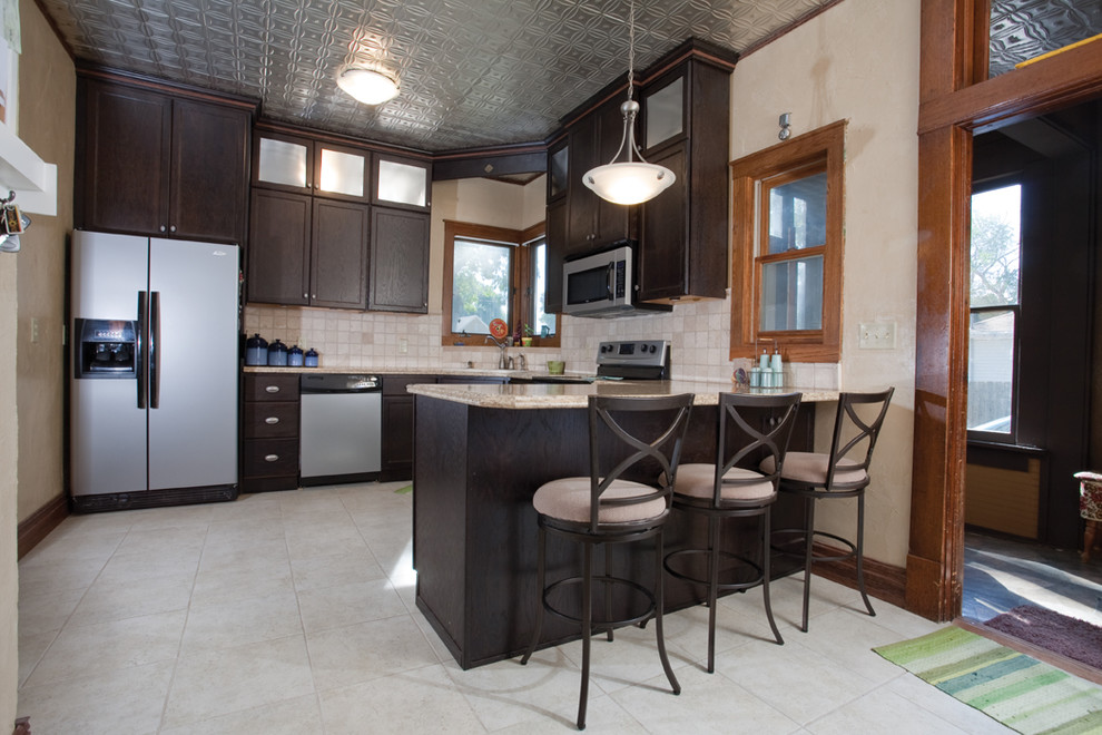 Mid-sized elegant l-shaped enclosed kitchen photo in Other with recessed-panel cabinets, dark wood cabinets, laminate countertops, stainless steel appliances, beige backsplash and a peninsula