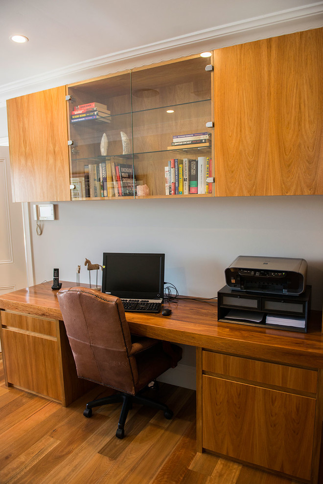 Diseño de despacho tradicional grande sin chimenea con paredes marrones, escritorio empotrado y suelo de travertino