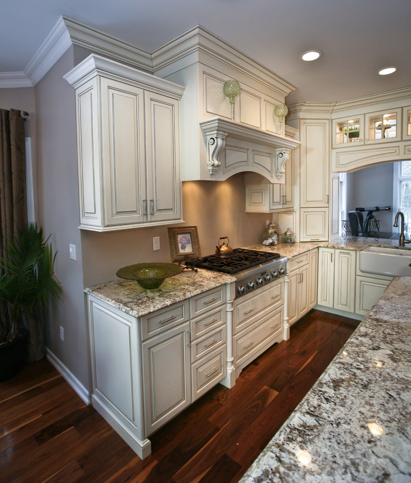 Mid-sized elegant u-shaped plywood floor eat-in kitchen photo in New York with a farmhouse sink, raised-panel cabinets, stainless steel appliances and an island