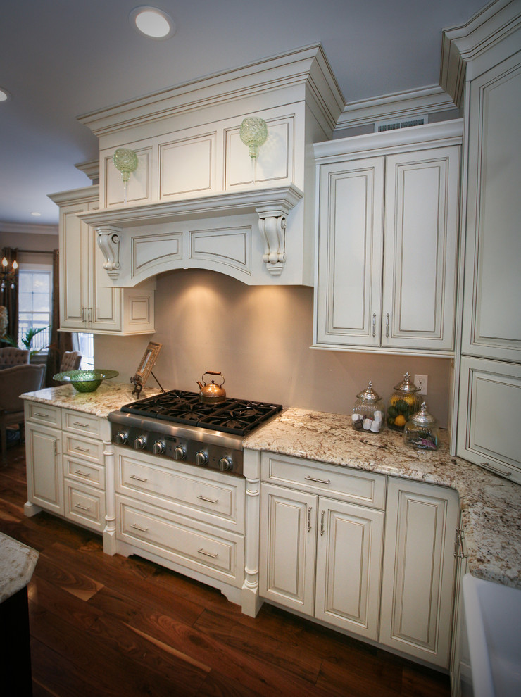 Example of a mid-sized classic u-shaped plywood floor eat-in kitchen design in New York with a farmhouse sink, raised-panel cabinets, stainless steel appliances and an island