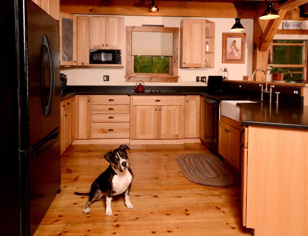 Foto de cocina clásica con fregadero sobremueble, puertas de armario de madera clara, electrodomésticos negros, suelo de madera clara, península y armarios con paneles empotrados