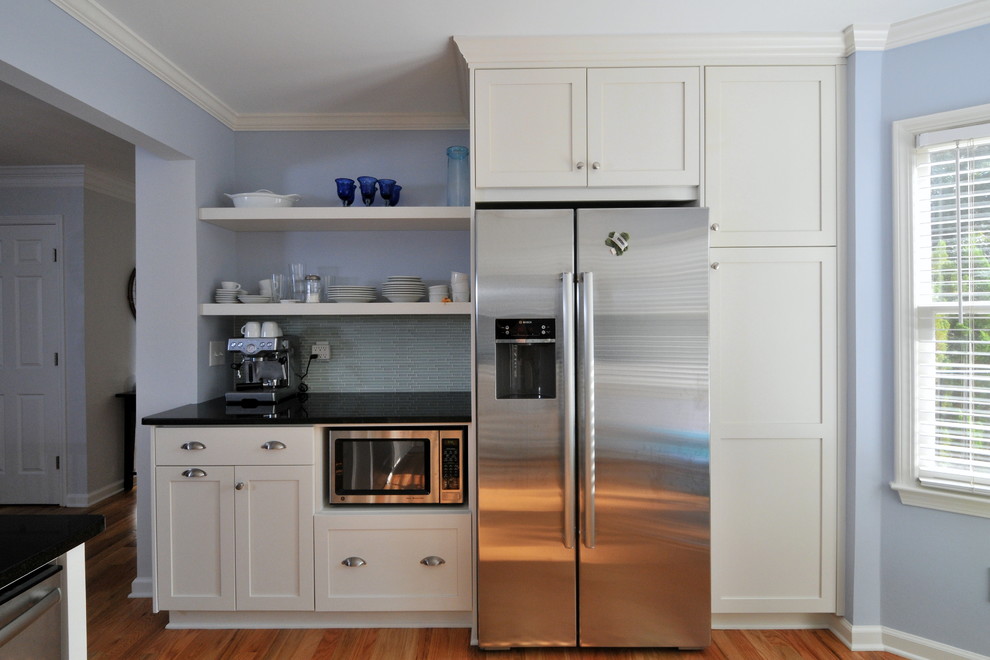 Diseño de cocina clásica con electrodomésticos de acero inoxidable, armarios estilo shaker, puertas de armario blancas, salpicadero azul y salpicadero de azulejos en listel