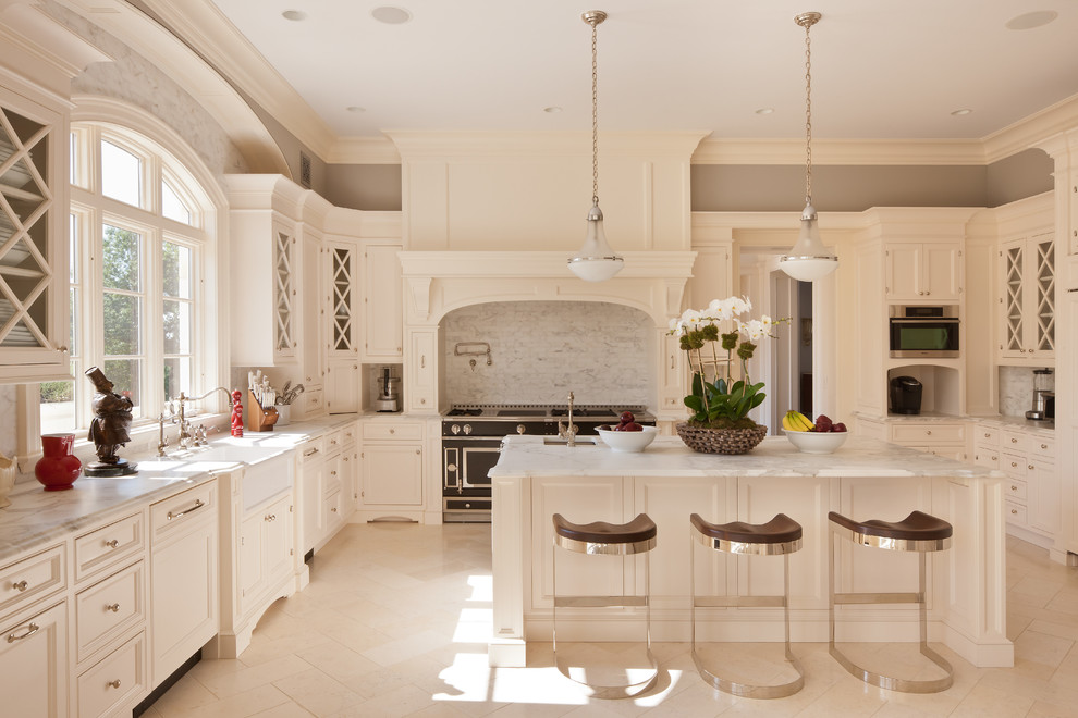 Klassische Küche in U-Form mit Landhausspüle, Schrankfronten mit vertiefter Füllung, weißen Schränken, Küchenrückwand in Grau und schwarzen Elektrogeräten in New York