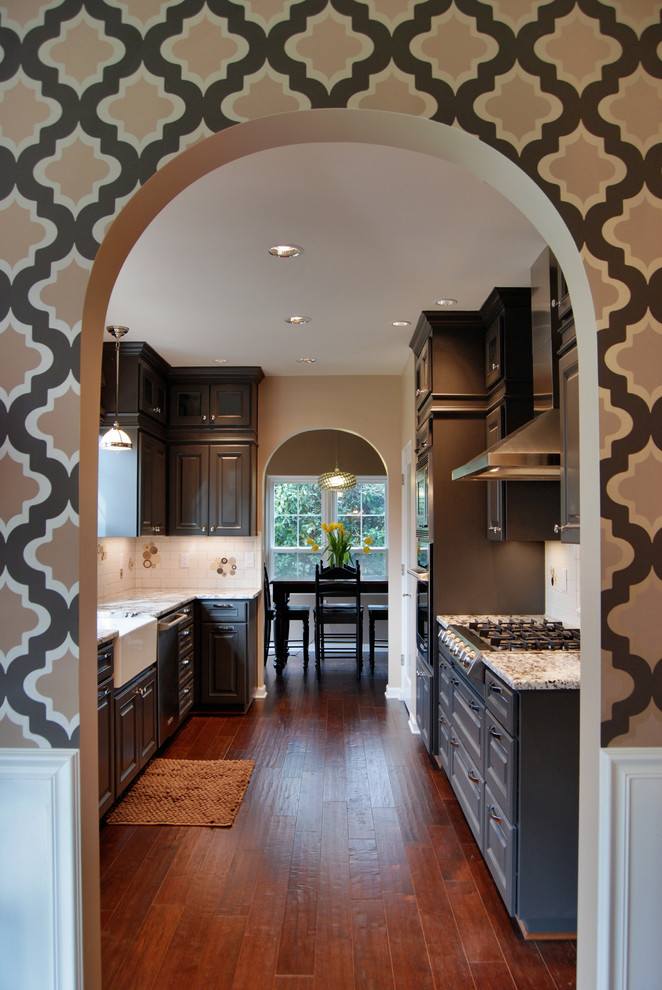 Inspiration for a timeless galley enclosed kitchen remodel in Other with raised-panel cabinets, gray cabinets, a farmhouse sink, granite countertops, white backsplash, ceramic backsplash and stainless steel appliances