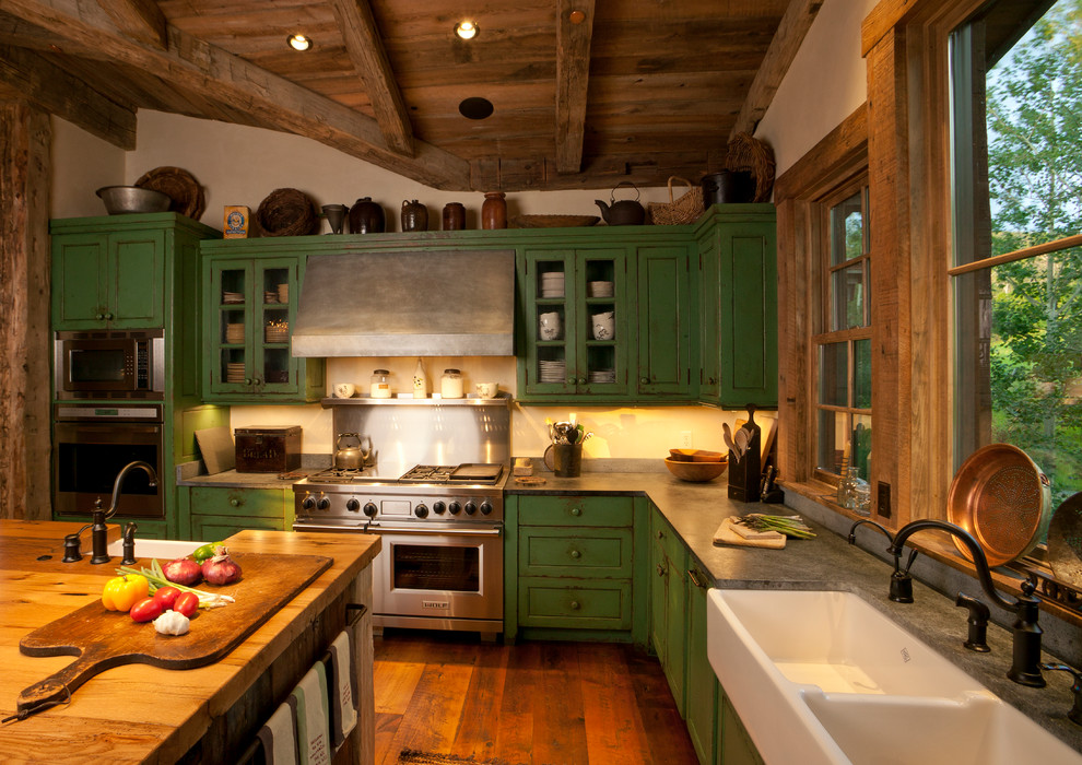 Große Klassische Küche in L-Form mit Doppelwaschbecken, Arbeitsplatte aus Holz, Rückwand aus Metallfliesen, Küchengeräten aus Edelstahl, Schrankfronten im Shaker-Stil, grünen Schränken, braunem Holzboden und Kücheninsel in Sonstige