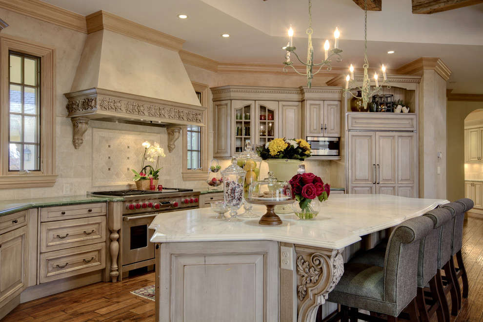 Immagine di una cucina classica con ante con bugna sagomata, ante beige, paraspruzzi beige, paraspruzzi con piastrelle in pietra e elettrodomestici in acciaio inossidabile
