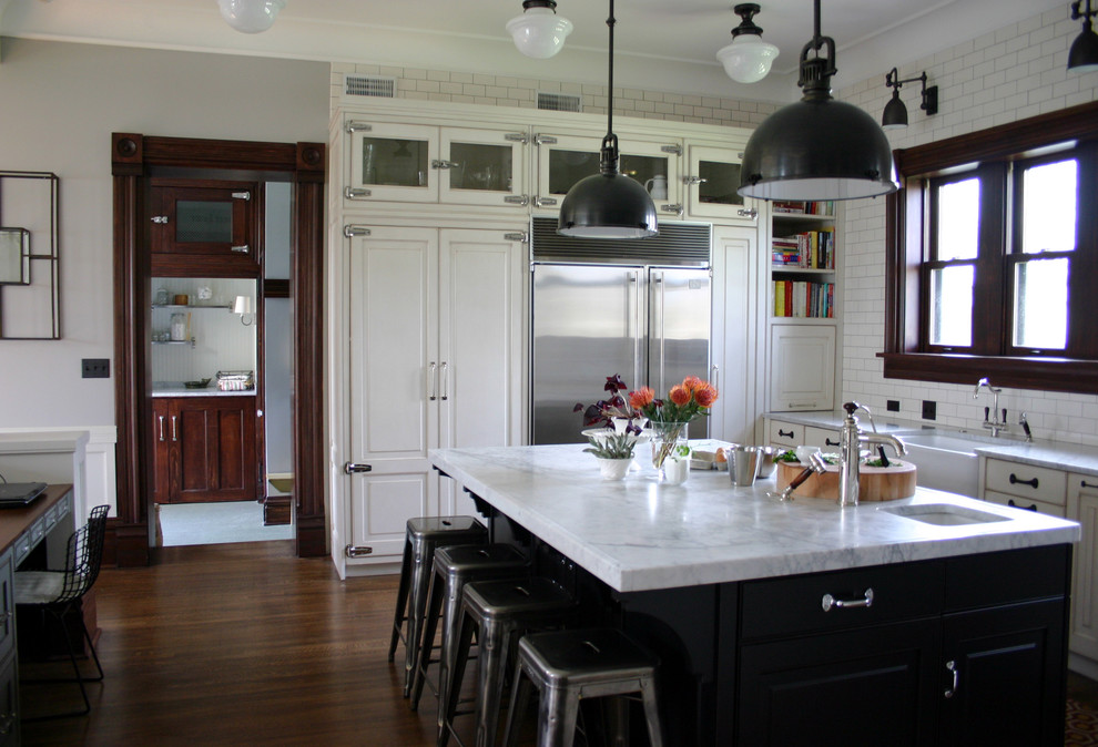 Klassisk inredning av ett kök, med stänkskydd i tunnelbanekakel, en rustik diskho, vita skåp, vitt stänkskydd, rostfria vitvaror, marmorbänkskiva och luckor med profilerade fronter