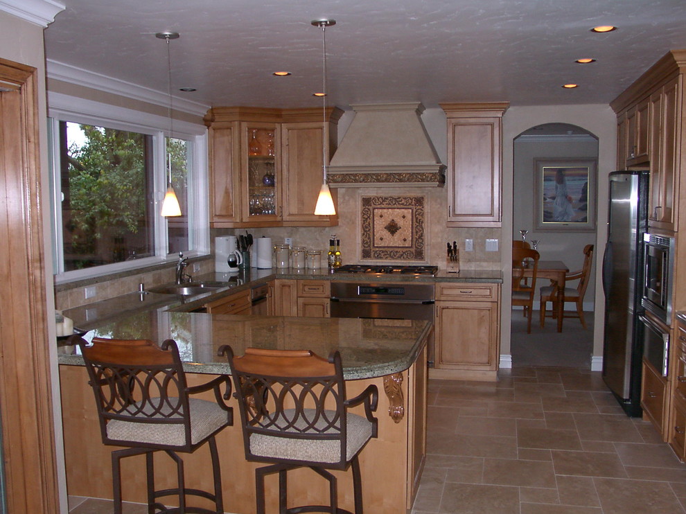 Foto på ett mellanstort vintage kök, med en undermonterad diskho, luckor med infälld panel, skåp i ljust trä, granitbänkskiva, beige stänkskydd, stänkskydd i stenkakel, rostfria vitvaror, travertin golv och en halv köksö
