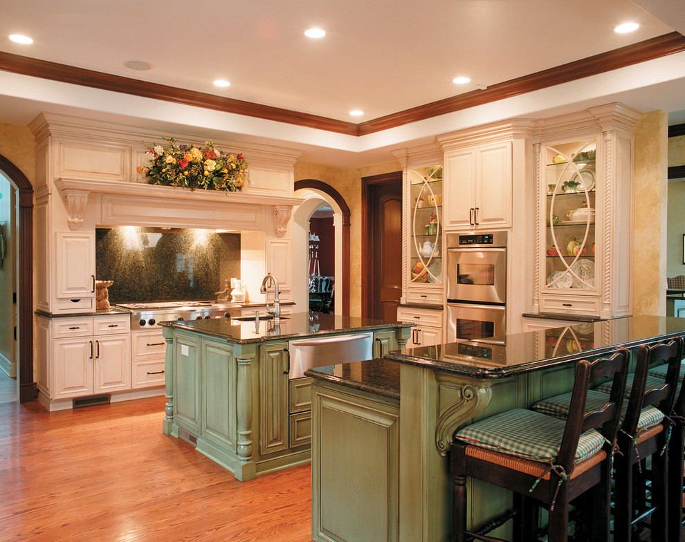 Kitchen - traditional kitchen idea in Other with raised-panel cabinets, stainless steel appliances, green cabinets, black backsplash and stone slab backsplash