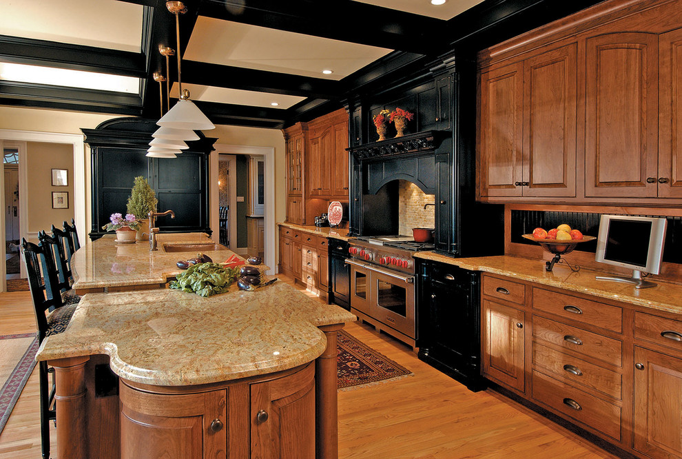 Imagen de cocina tradicional abierta con electrodomésticos de acero inoxidable, armarios con rebordes decorativos, puertas de armario de madera oscura y barras de cocina