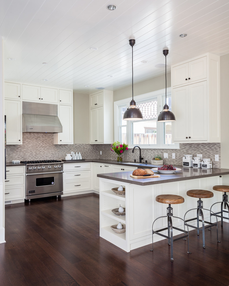 This is an example of a medium sized classic u-shaped open plan kitchen in San Francisco with a built-in sink, shaker cabinets, white cabinets, engineered stone countertops, beige splashback, stainless steel appliances, medium hardwood flooring and a breakfast bar.