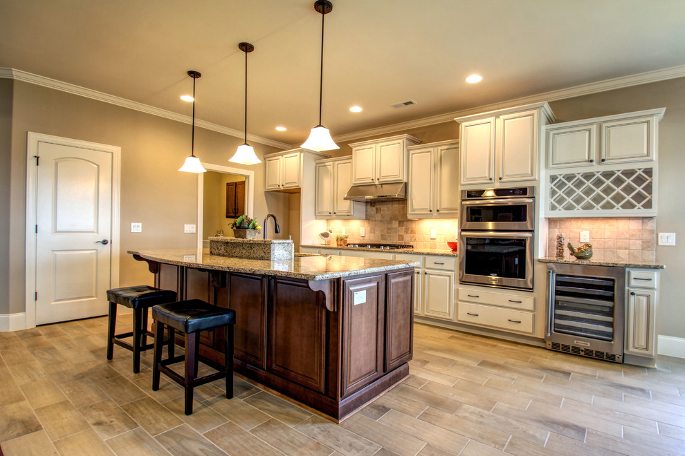 Example of a mid-sized classic single-wall ceramic tile eat-in kitchen design in Wilmington with an undermount sink, raised-panel cabinets, beige cabinets, granite countertops, beige backsplash, stone tile backsplash, stainless steel appliances and an island