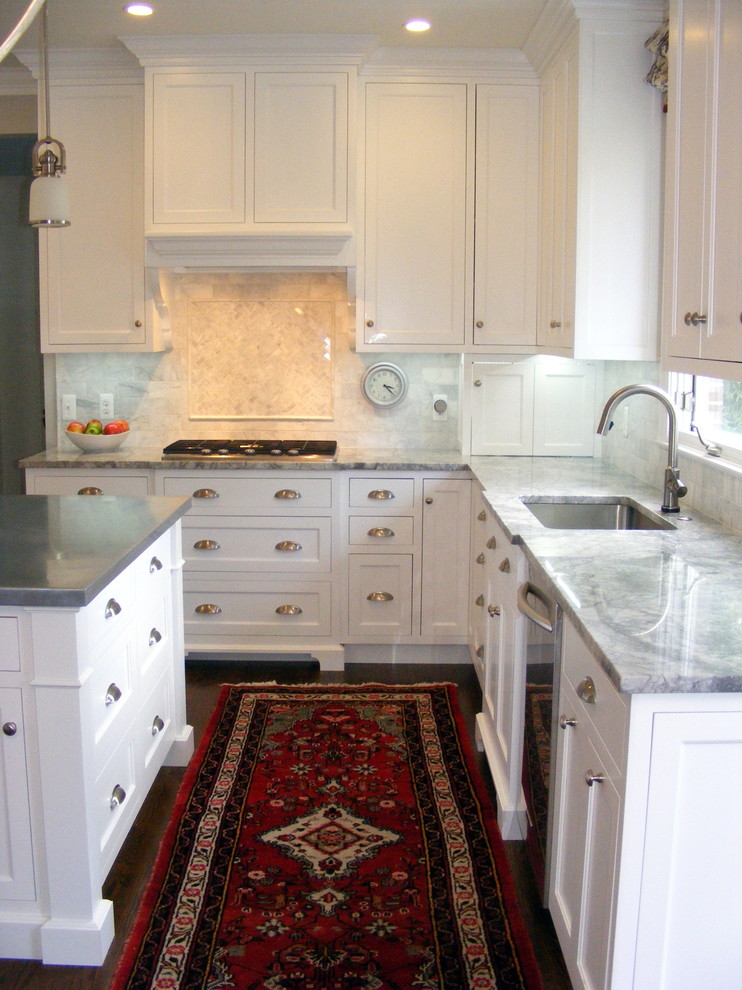 Bild på ett mellanstort vintage kök, med luckor med infälld panel, vita skåp, marmorbänkskiva, grått stänkskydd, stänkskydd i stenkakel, en köksö, en undermonterad diskho, mörkt trägolv, rostfria vitvaror och brunt golv
