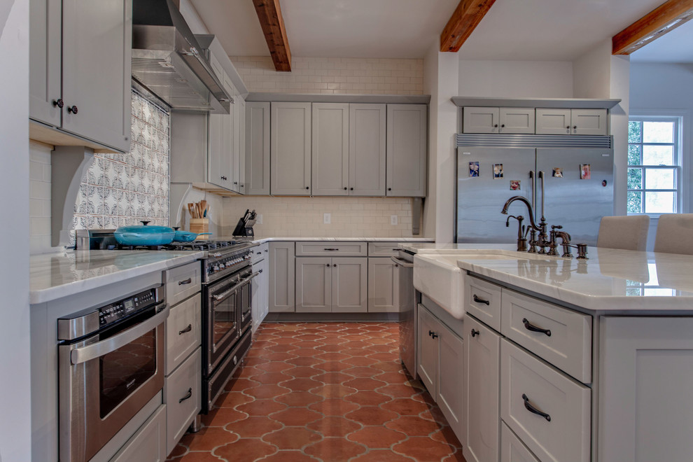 Inredning av ett klassiskt kök, med en rustik diskho, skåp i shakerstil, grå skåp, granitbänkskiva, rostfria vitvaror och klinkergolv i keramik