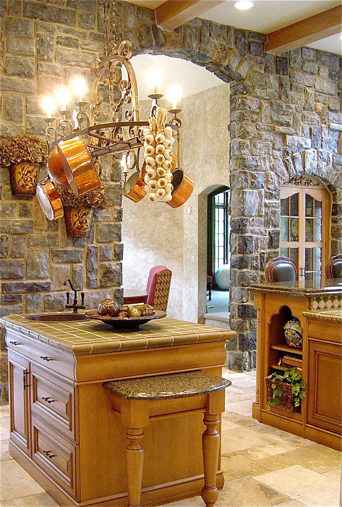 Cette photo montre une grande cuisine chic en bois brun fermée avec un évier de ferme, un placard avec porte à panneau surélevé, plan de travail carrelé et un électroménager en acier inoxydable.
